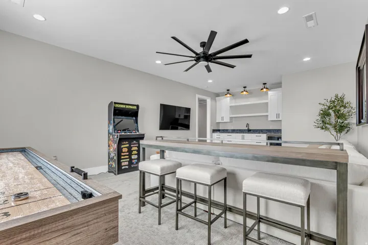 Recessed lighting, ceiling fan, built-in wet bar with white cabinetry, open shelving, and dark-toned backsplash