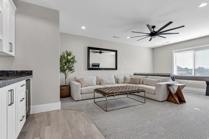 Recessed lighting, a modern ceiling fan, and a built-in wet bar with white cabinetry, dark countertops, and wood-finish flooring