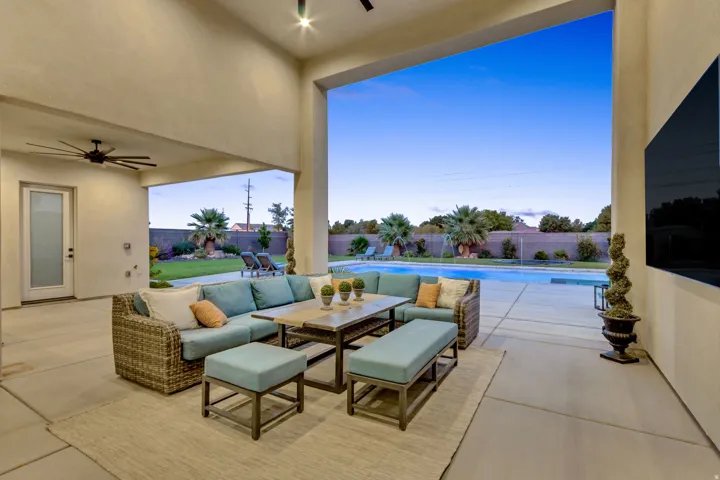 Expansive outdoor living area with a covered patio, ceiling fan, and recessed lighting
