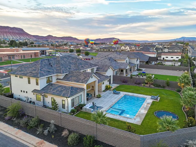 Expansive backyard featuring a swimming pool with integrated spa, manicured lawn, and mature palm trees