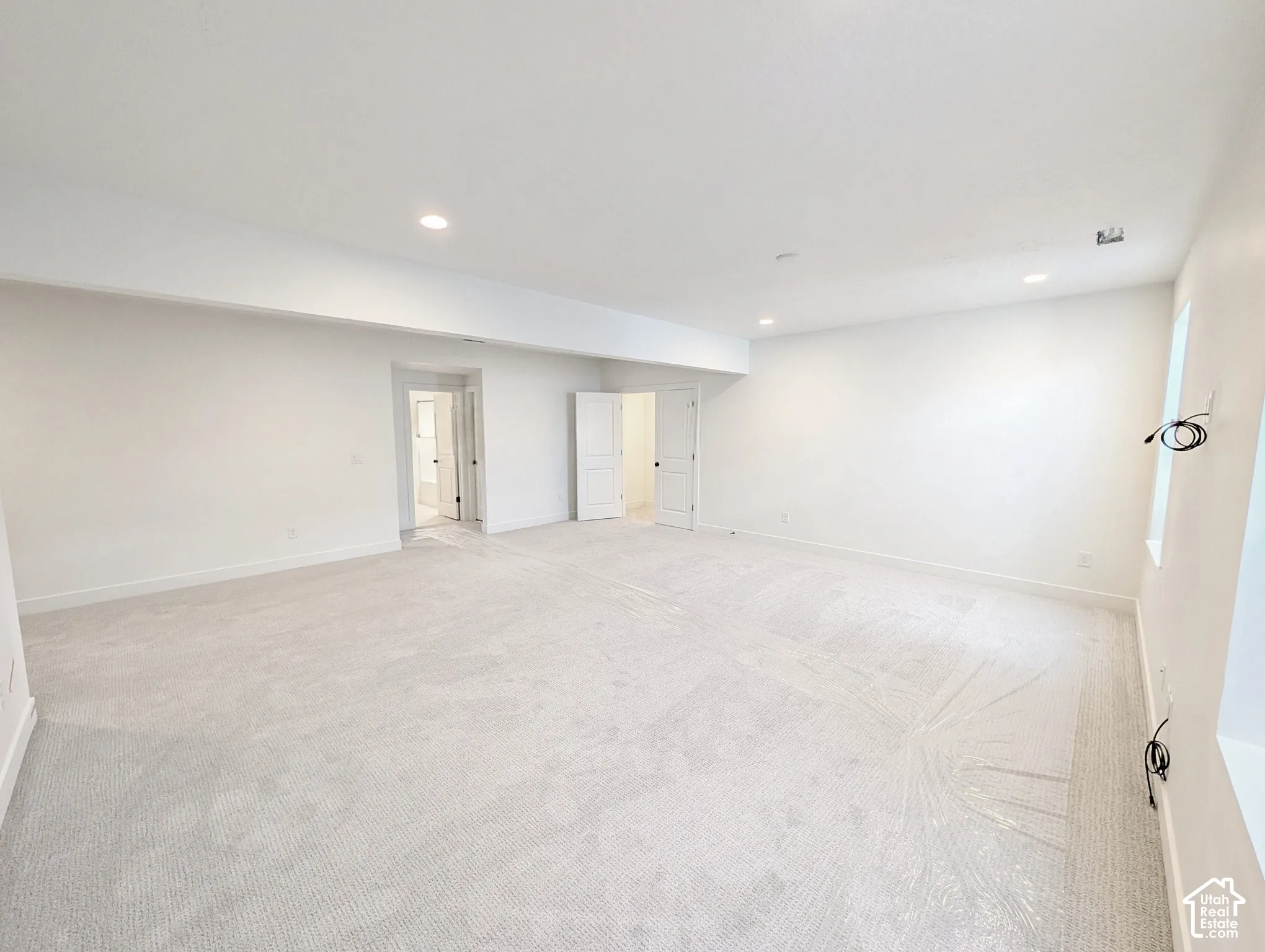 Spacious room featuring light-toned carpeting and recessed lighting