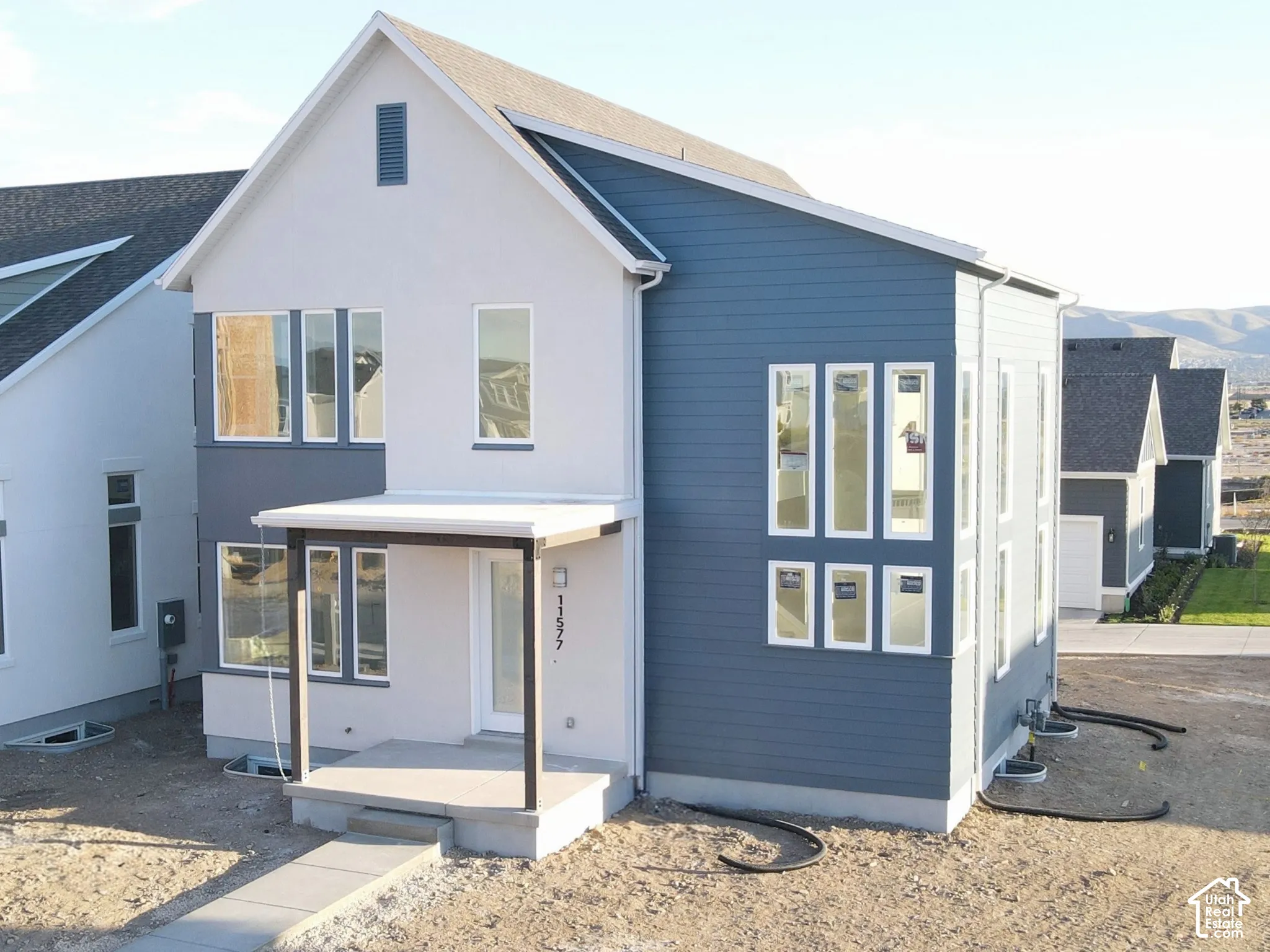 Contemporary two-story residence with a covered front porch, a combination of horizontal siding and stucco exterior, and multiple vertical windows