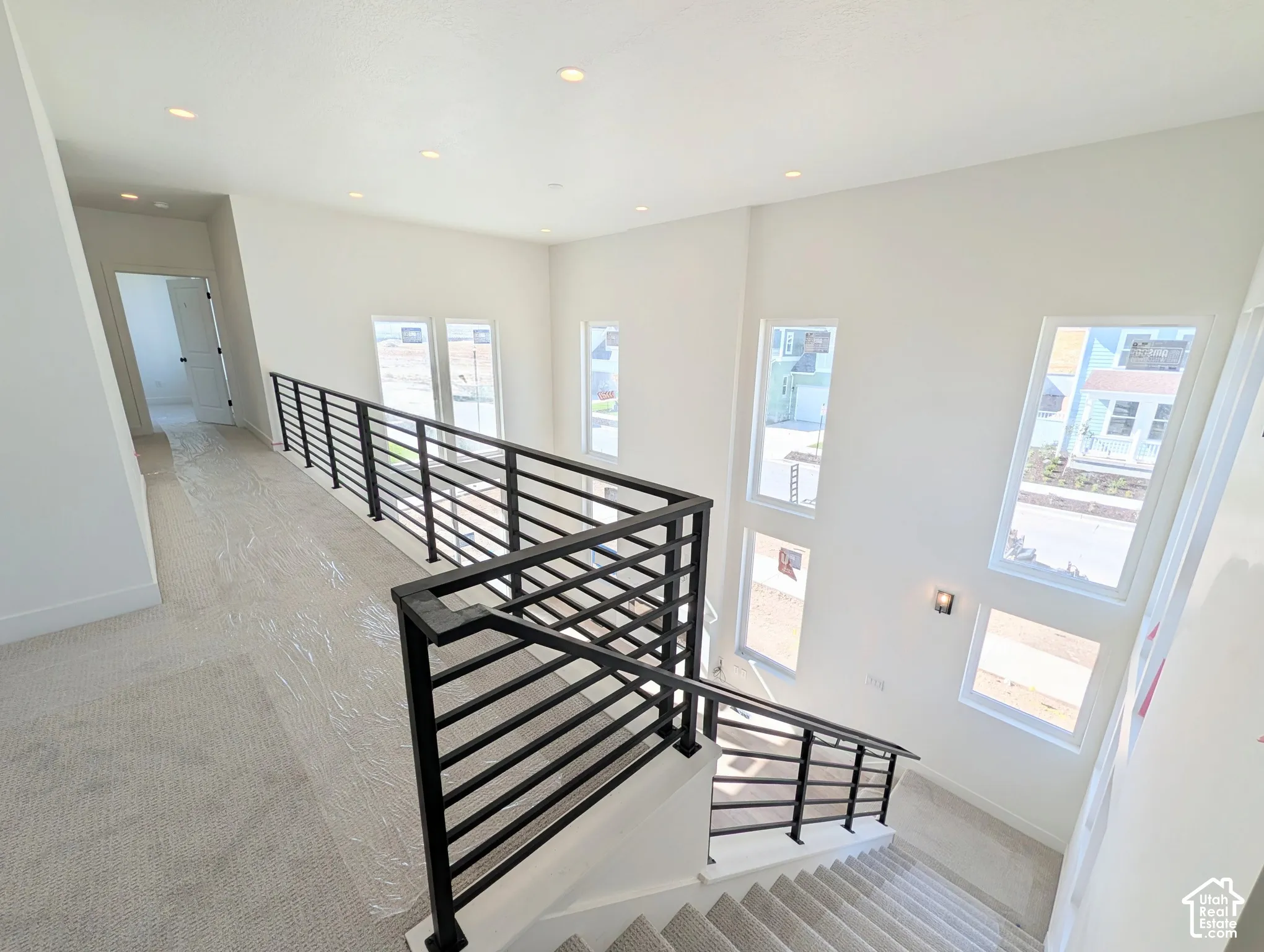 High ceilings, modern black metal railings, recessed lighting, and multiple windows