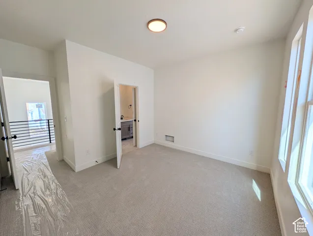 Plush carpet flooring, neutral paint palette, recessed lighting, and a window for natural illumination
