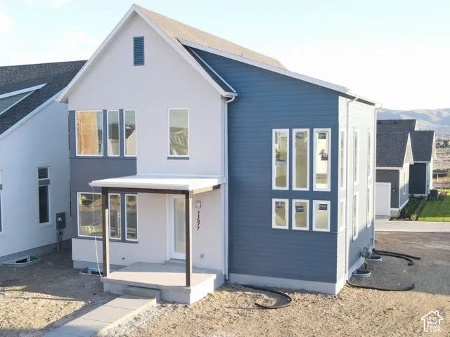 Contemporary two-story residence with a covered front porch, a combination of horizontal siding and stucco exterior, and multiple vertical windows
