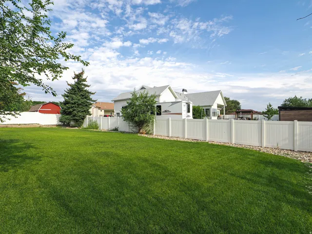 Expansive lawn area enclosed by a white privacy fence