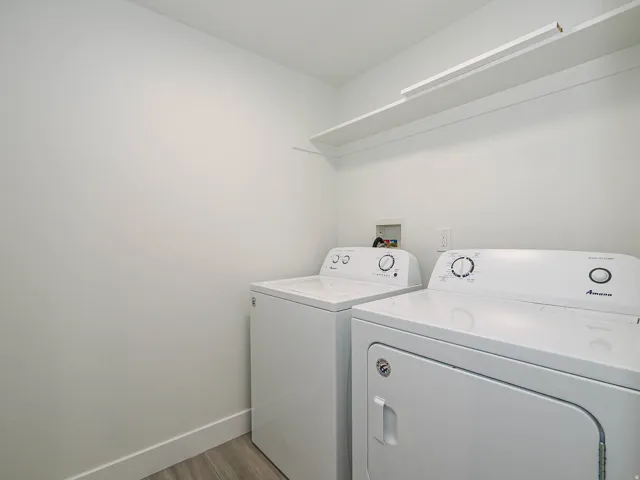 Laundry area with light wood-finish flooring, white walls, and an integrated white shelf