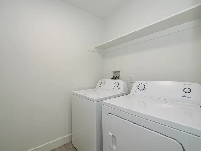 Laundry area featuring a built-in shelf, neutral wall tones, and wood-finish flooring