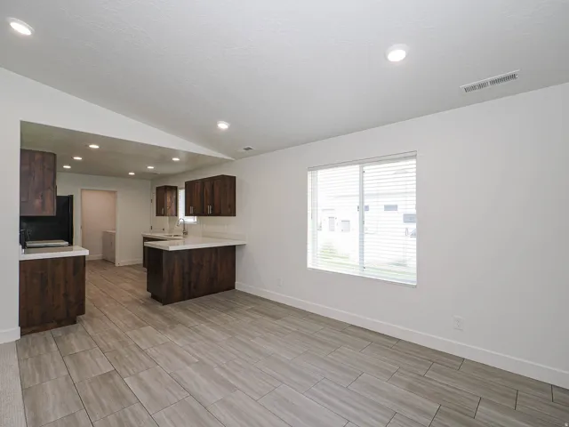 Spacious room featuring tile flooring, a large window, recessed lighting, and white walls