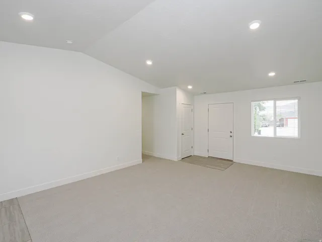 Recessed lighting, light-toned carpeting, white walls, and a multi-pane window