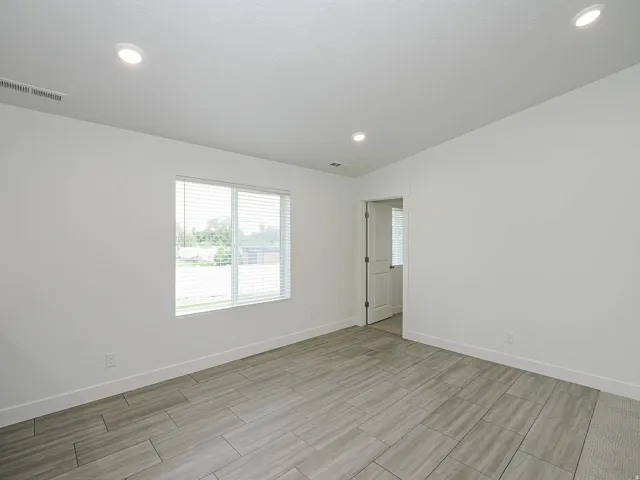 Recessed ceiling lighting, durable tile flooring, white walls, and a window with blinds