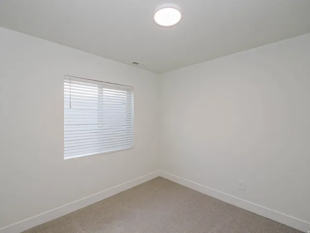 Recessed ceiling light, neutral wall paint, window with horizontal blinds, and carpeted flooring