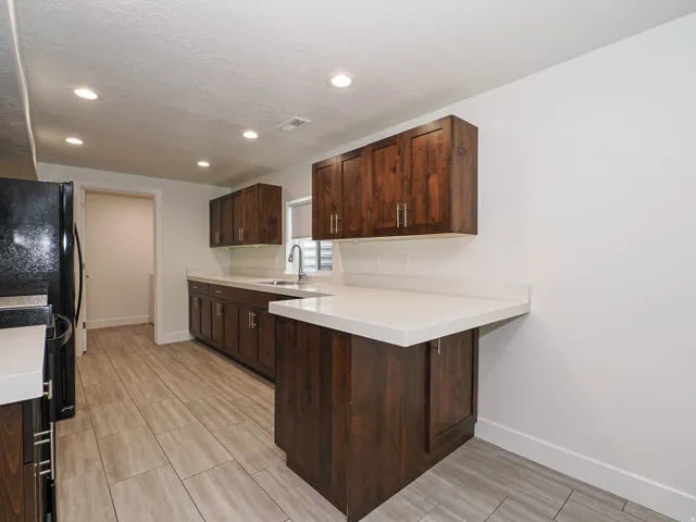 Kitchen featuring dark wood cabinetry, white countertops, stainless steel sink with a gooseneck faucet, and recessed lighting