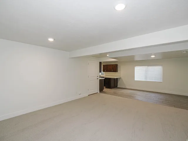 Recessed lighting, light-toned carpeting, dark wood-finish cabinetry, light-toned countertop, and tile flooring