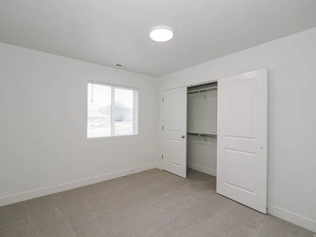 Neutral-toned carpeting, white walls, and a window with blinds