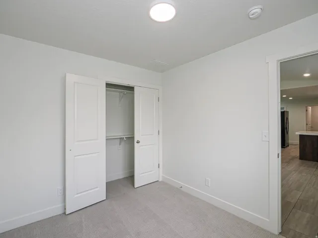 White walls, recessed lighting, and a closet with bifold doors