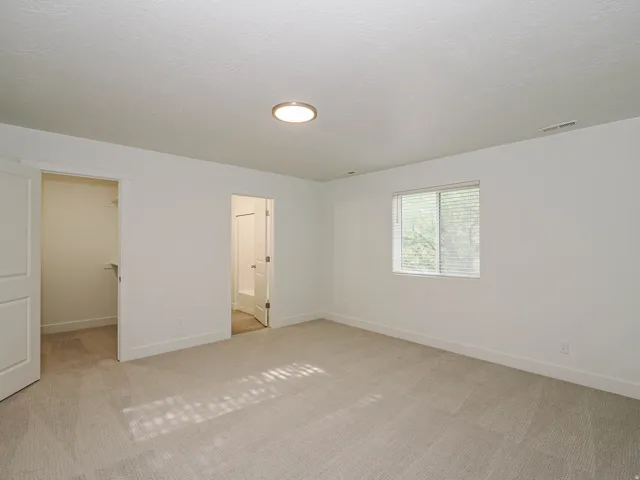 Neutral-toned carpet flooring, white walls, and a flush-mount ceiling light