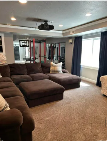 Recessed lighting, ceiling-mounted projector, carpeted flooring, and window with dark drapes