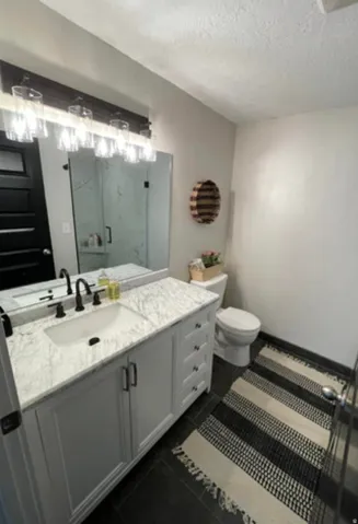 White vanity with a stone countertop, an undermount sink, and matte black fixtures