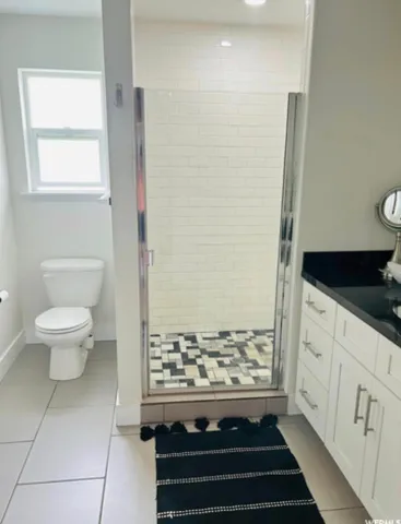 Glass-enclosed shower with subway tile surround and patterned shower floor