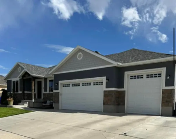Exterior featuring a split three-car garage, stone and stucco facade, partial shake siding, and a covered entry