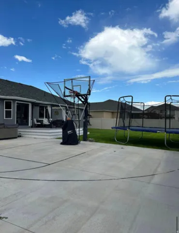Spacious concrete patio with court markings, multi-level composite deck, and manicured lawn