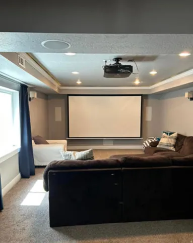 Built-in projection screen with a ceiling-mounted projector, recessed lighting, integrated ceiling speakers, and wall-mounted speakers