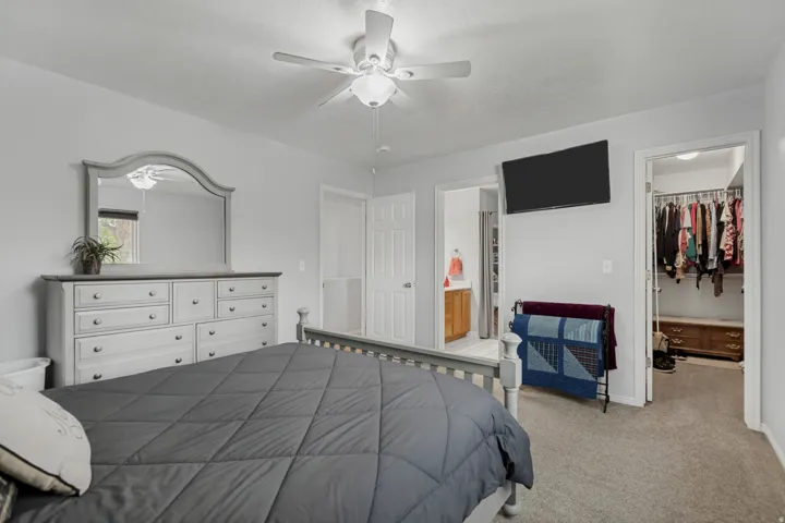 Plush carpet flooring, ceiling fan, and access to an adjoining bathroom