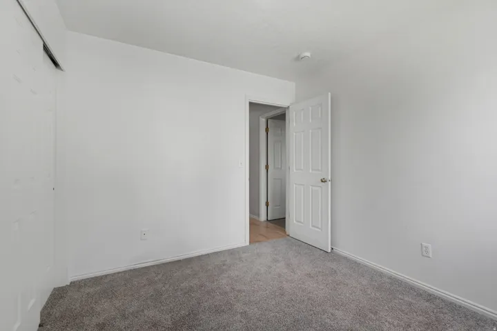 Grey carpeting, white painted walls, and a five-panel interior door