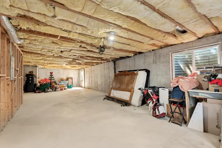Unfinished basement space featuring concrete walls, concrete flooring, and exposed ceiling insulation