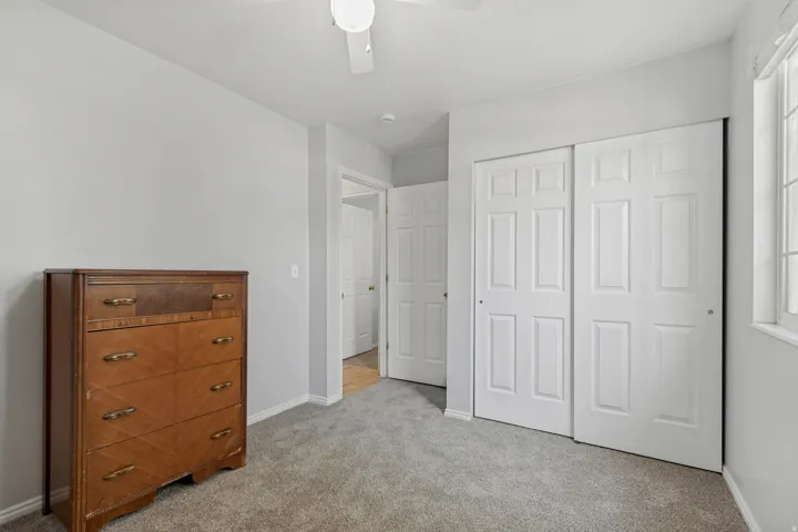 Gray wall finish with a white ceiling, light gray carpet, and white paneled bi-fold closet doors
