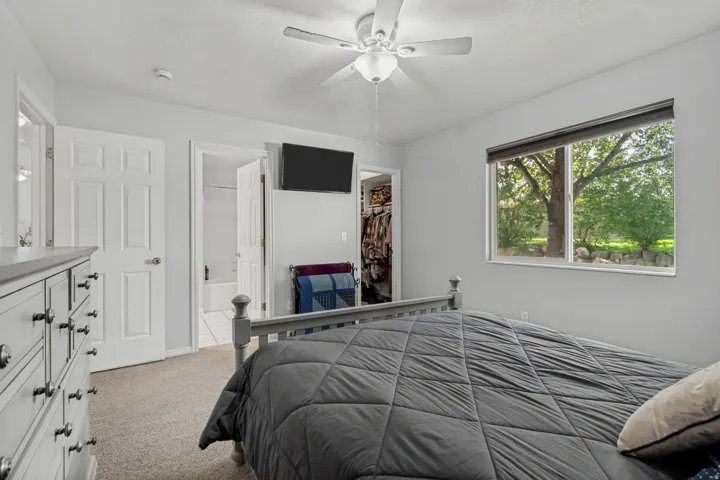 Carpeted room with a ceiling fan, a window, and a built-in closet