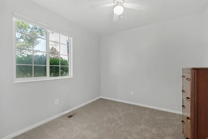 Carpeted flooring, white walls, white trim, and a white ceiling fan