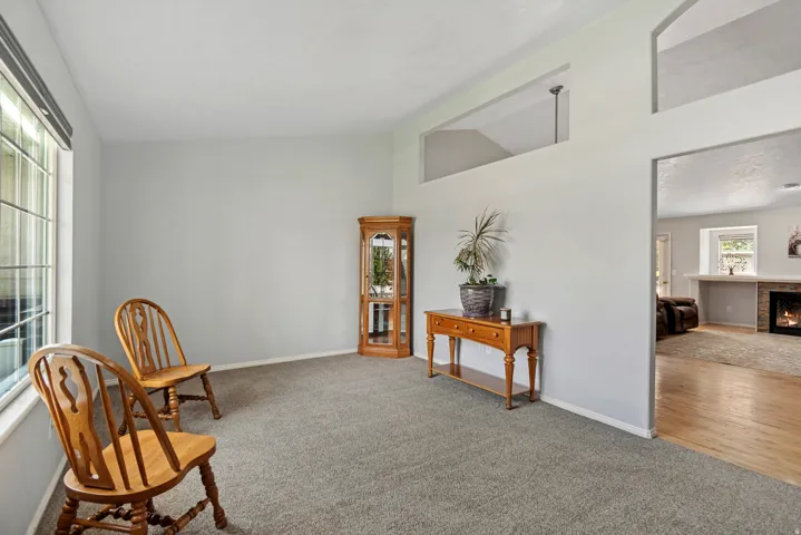 Carpeted flooring, vaulted ceiling, interior window, transom windows, and a doorway to an additional living space