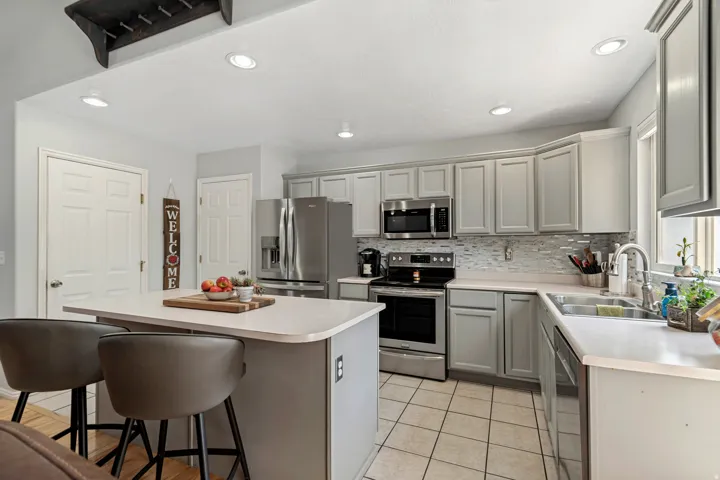Kitchen featuring light gray cabinetry, stainless steel appliances, a center island, a tiled backsplash, and recessed lighting