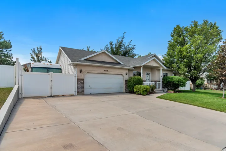 Exterior featuring a two-car garage, covered porch, and white fencing