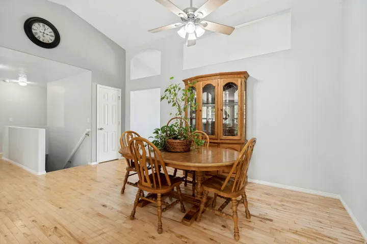 Vaulted ceilings with a ceiling fan, light wood-finish flooring, and a six-panel interior door