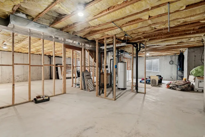 Spacious unfinished basement with exposed wood framing, concrete floor, and visible insulation