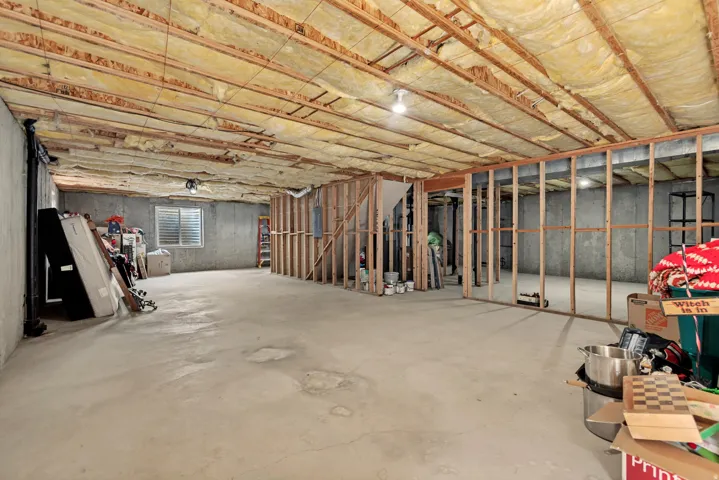Unfinished basement with concrete flooring, framed wall structures, and exposed ceiling joists with insulation