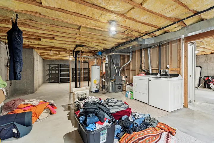 Unfinished basement with exposed ceiling joists and insulation
