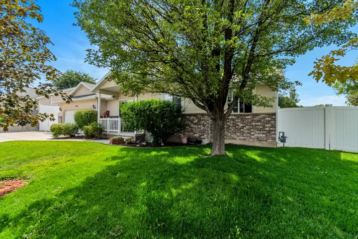 Property exterior featuring a covered porch, white railing, stucco and brick-veneer facade, and a white privacy fence