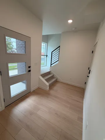 Entryway featuring wood-finish flooring, a modern glass-paneled entry door, recessed lighting, and a staircase with a contemporary black railing