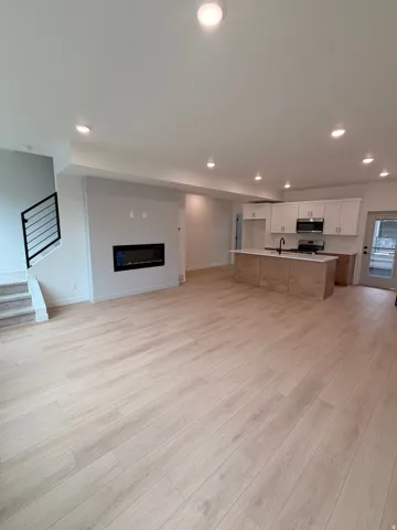 Open-concept living space featuring wood-finish flooring, recessed lighting, and a built-in fireplace