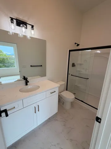 Primary bathroom. White vanity with integrated sink, quartz countertop, and matte black fixtures