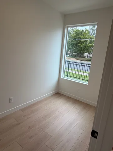 Office/den with hardwood-style flooring, a large window, white walls, and white trim
