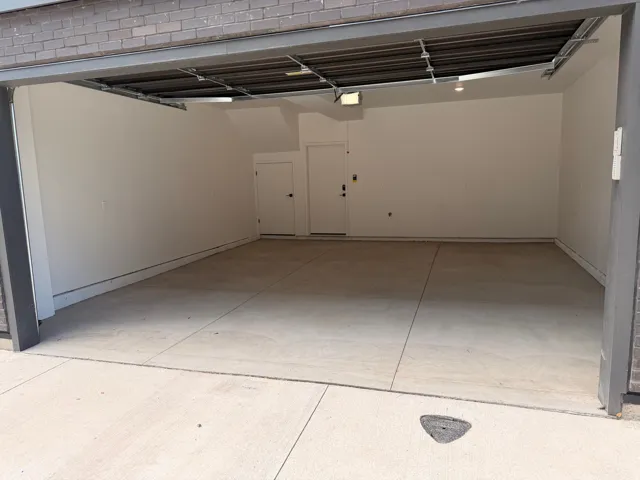 Attached garage with light-colored concrete flooring, white painted walls, and a visible ceiling-mounted light fixture