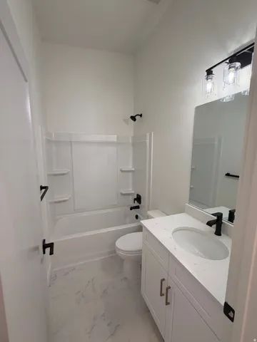 White vanity with brass-finish hardware, single basin sink, and solid surface countertop