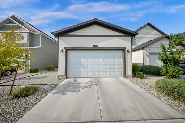 Attached two-car garage with a panel door, concrete driveway, and exterior wall sconces