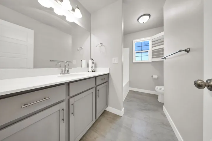 Dual-tone vanity with a white countertop and undermount sink, brushed nickel faucet, large mirror, and tiled flooring
