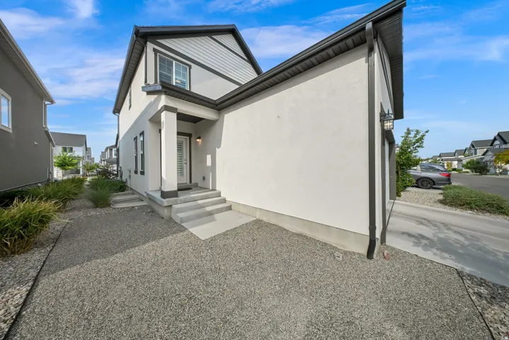 Contemporary exterior showcasing a stucco and siding facade, covered entry, concrete steps, and a gravel front yard